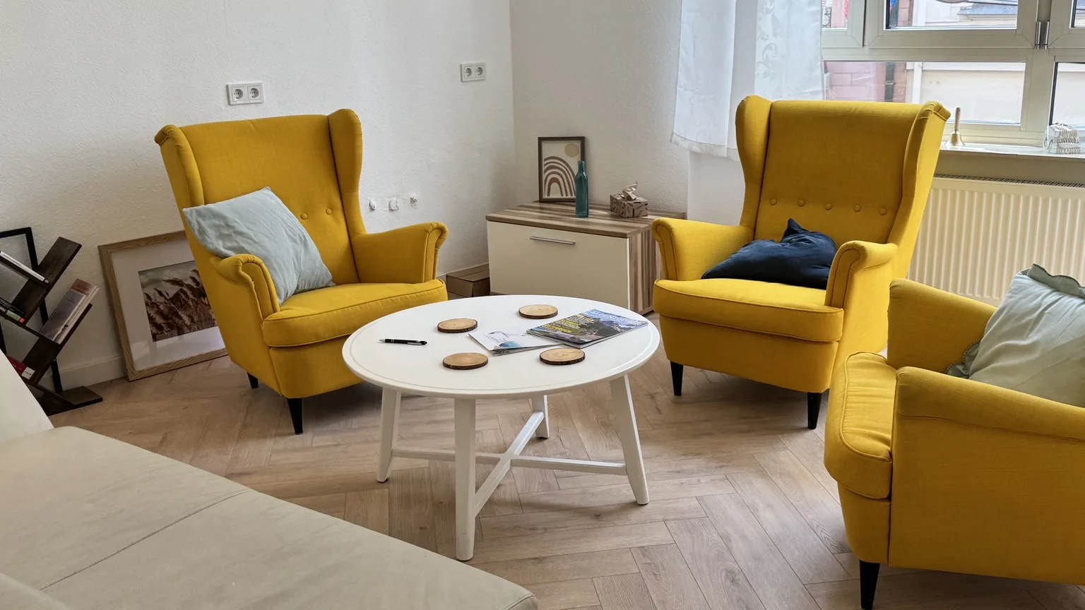 Heller Coachingraum mit drei gelben Sesseln und rundem Tisch in der DHI Hypnosepraxis Aschaffenburg