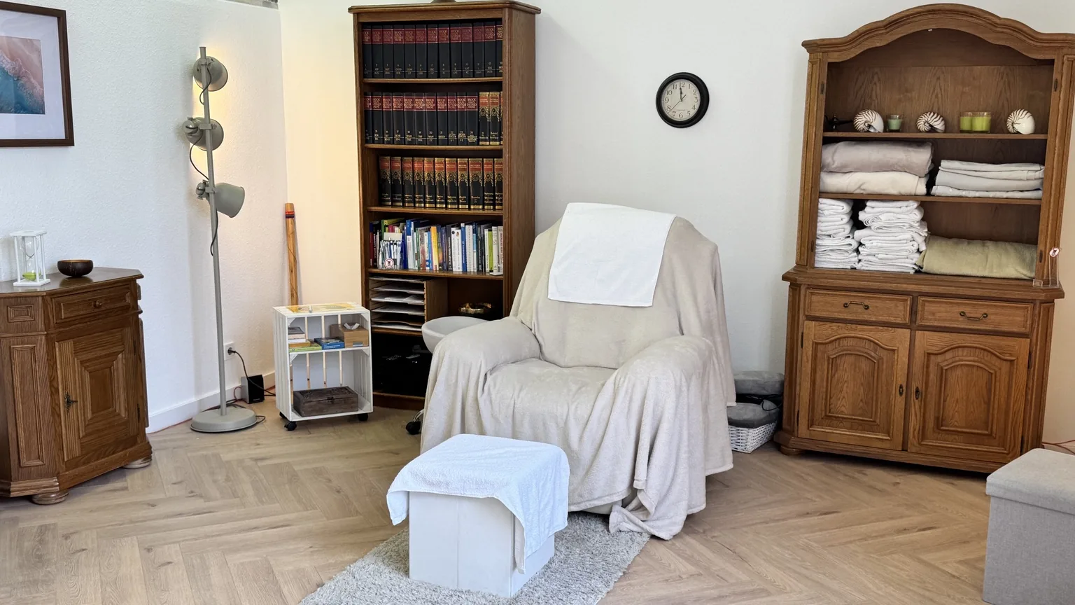 Hypnoseraum mit großem Hypnosesessel, Fußhocker, Regal und warmem Licht